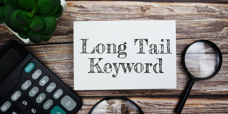 Long tail keyword text message with magnifying glass on wooden background.