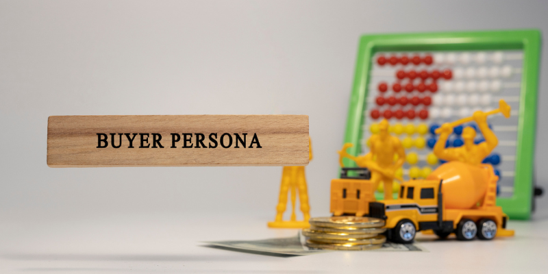Wooden sign reading 'Buyer Persona' propped up by a yellow toy figure, positioned near a yellow construction vehicle and a green-framed abacus.